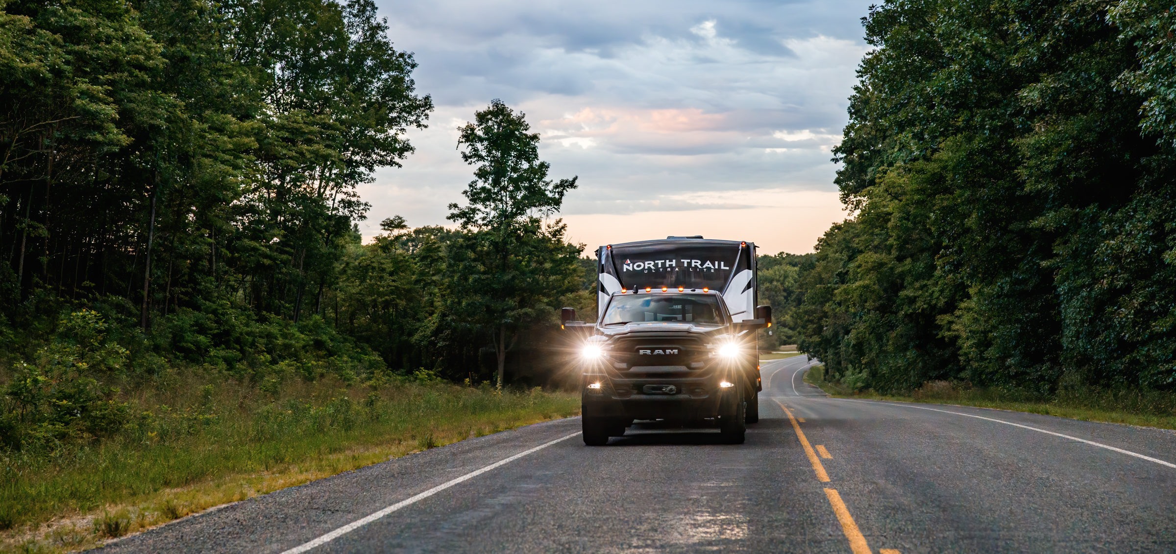A North Trail travel trailer towed by a truck on the road.