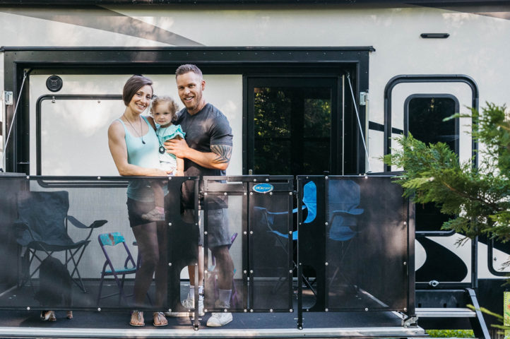 A couple holding a small child on the patio of an RV.